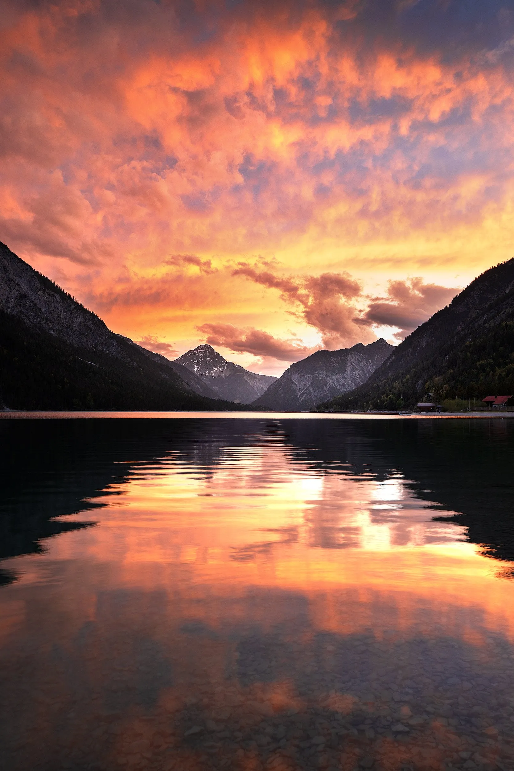 Mountain lake beneath an orange and pink evening sky.