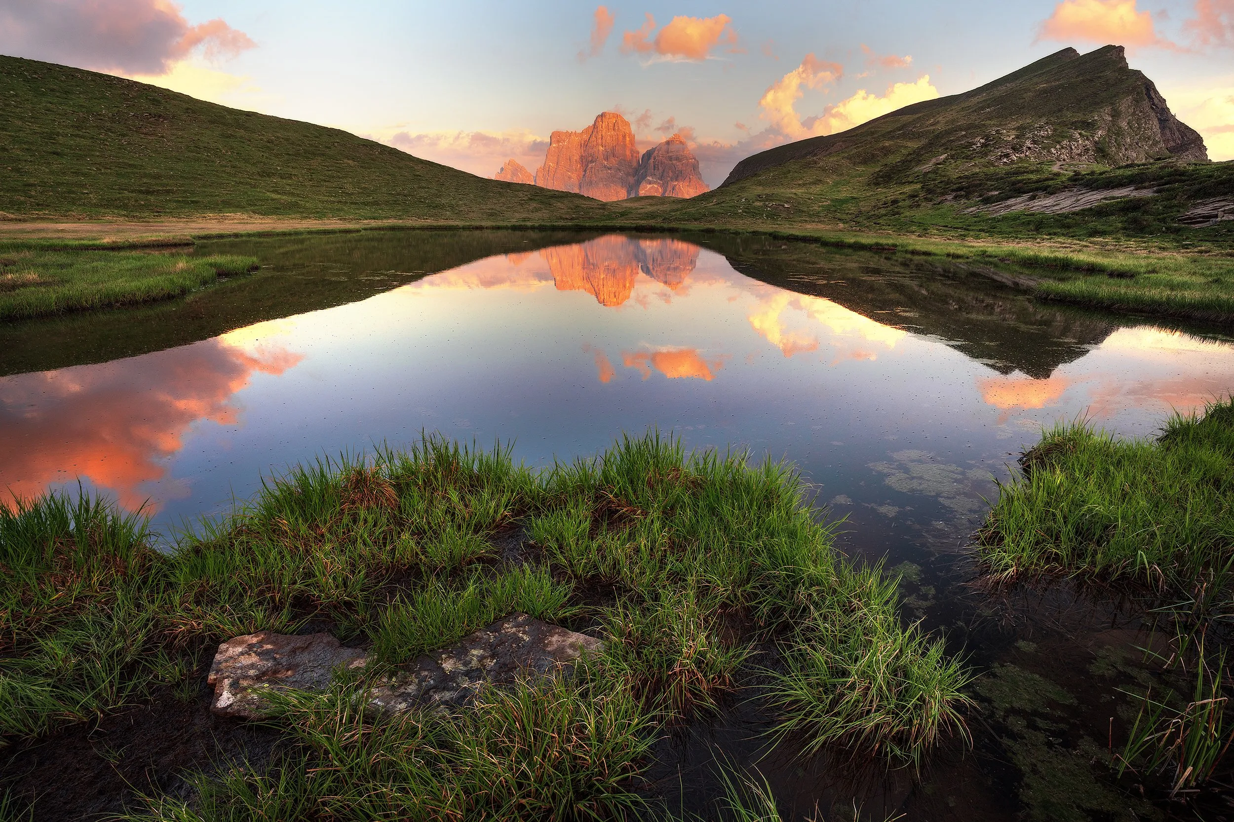 A quiet mountain valley, the lake mirroring a pastel sunset sky.