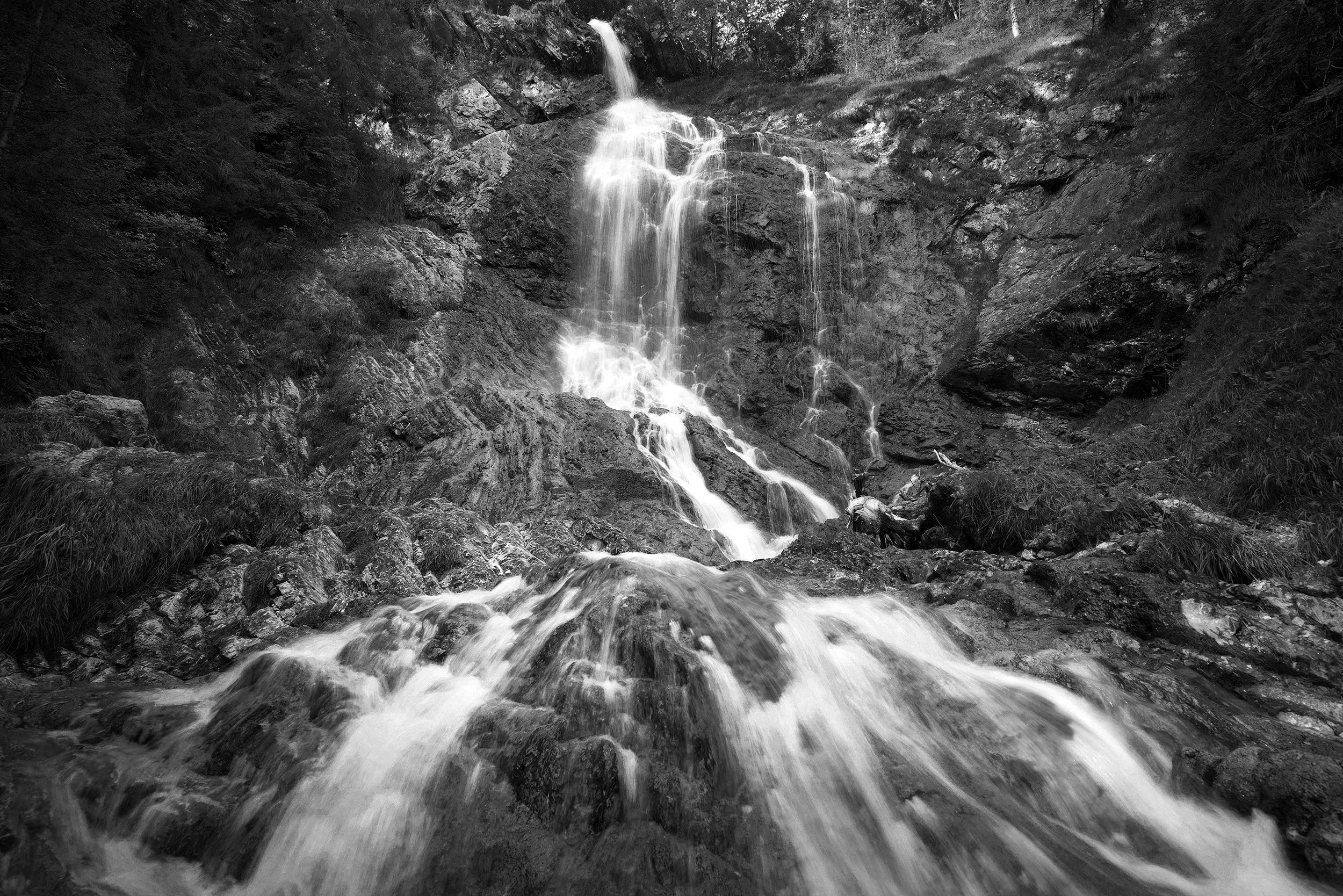 A waterfall over dark rock, in monochrome.
