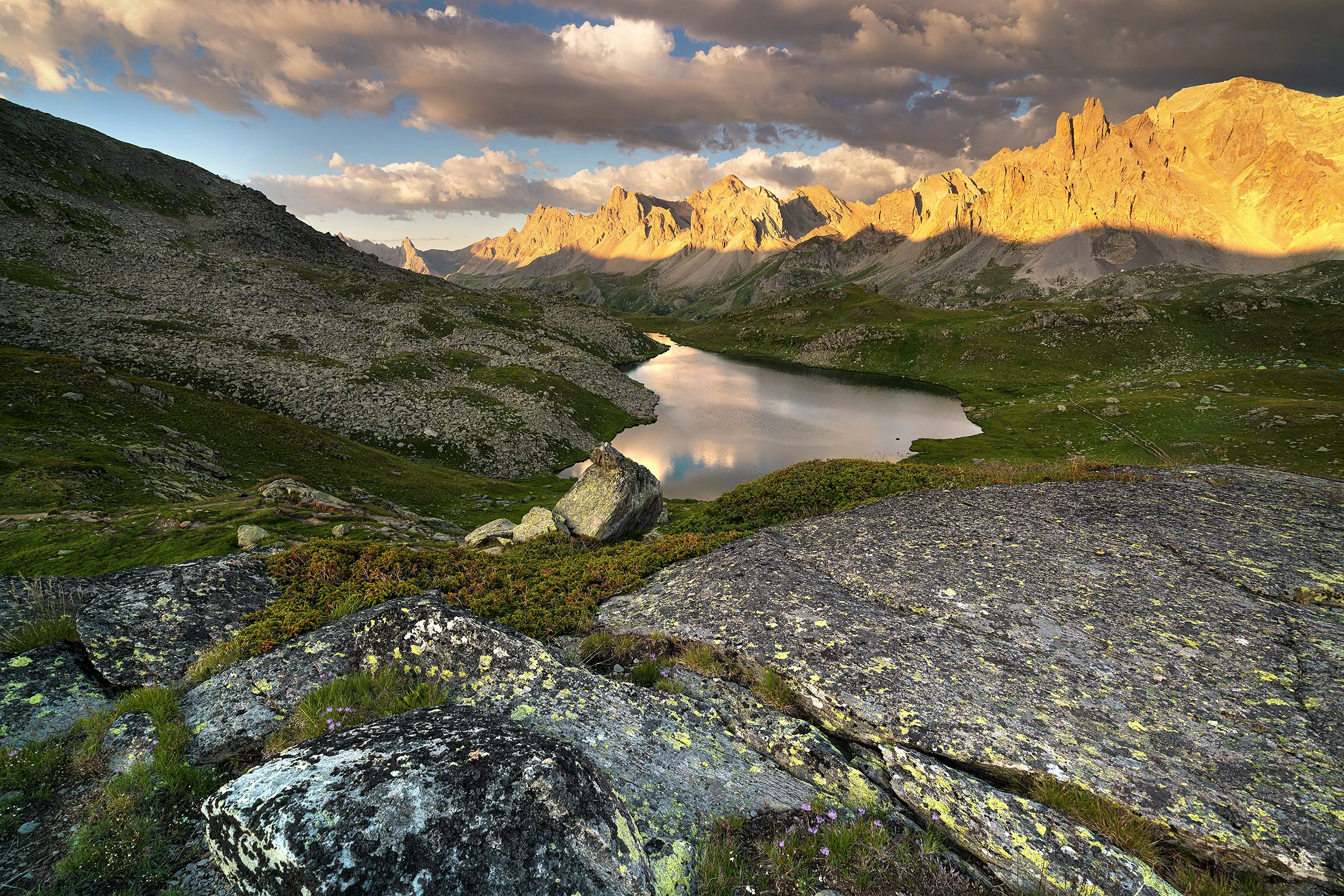 Rock faces lit gold above a still alpine lake.
