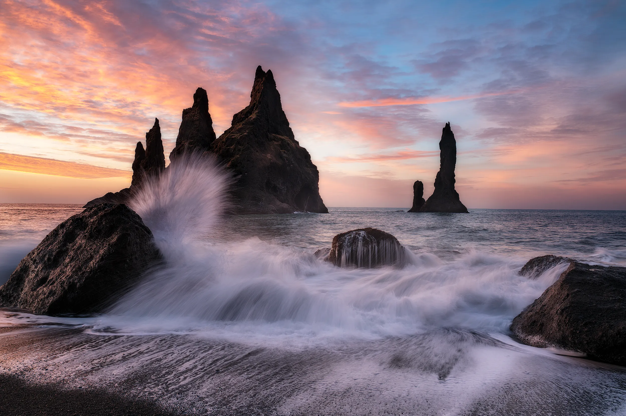 Basalt sea stacks, waves breaking under a dusk sky in full colour.
