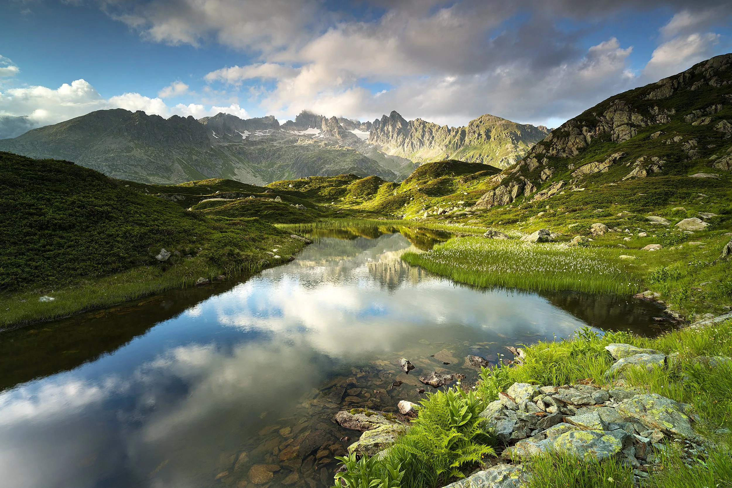 A mirror-still river through a green alpine valley.