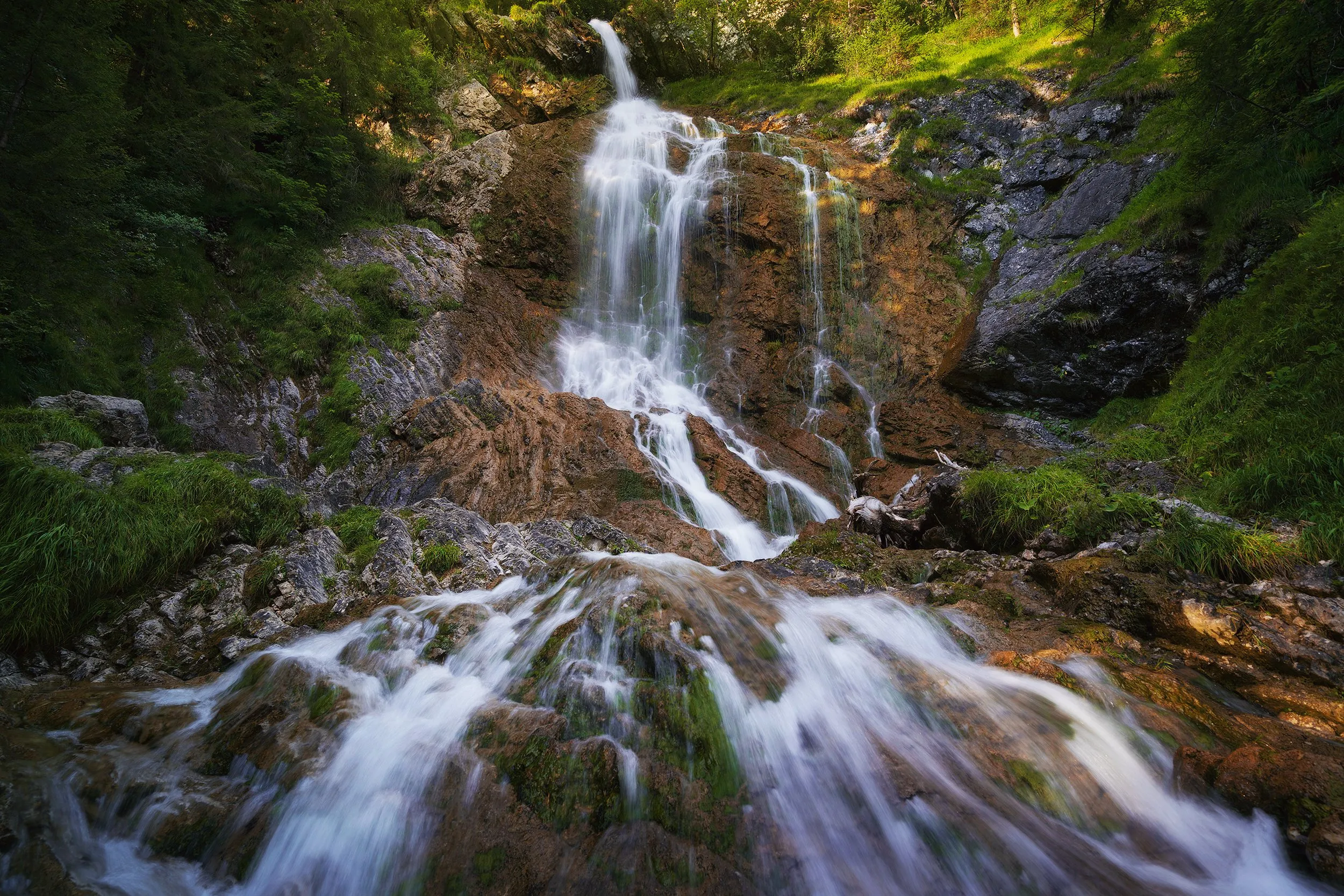 A waterfall dropping through dense green forest.