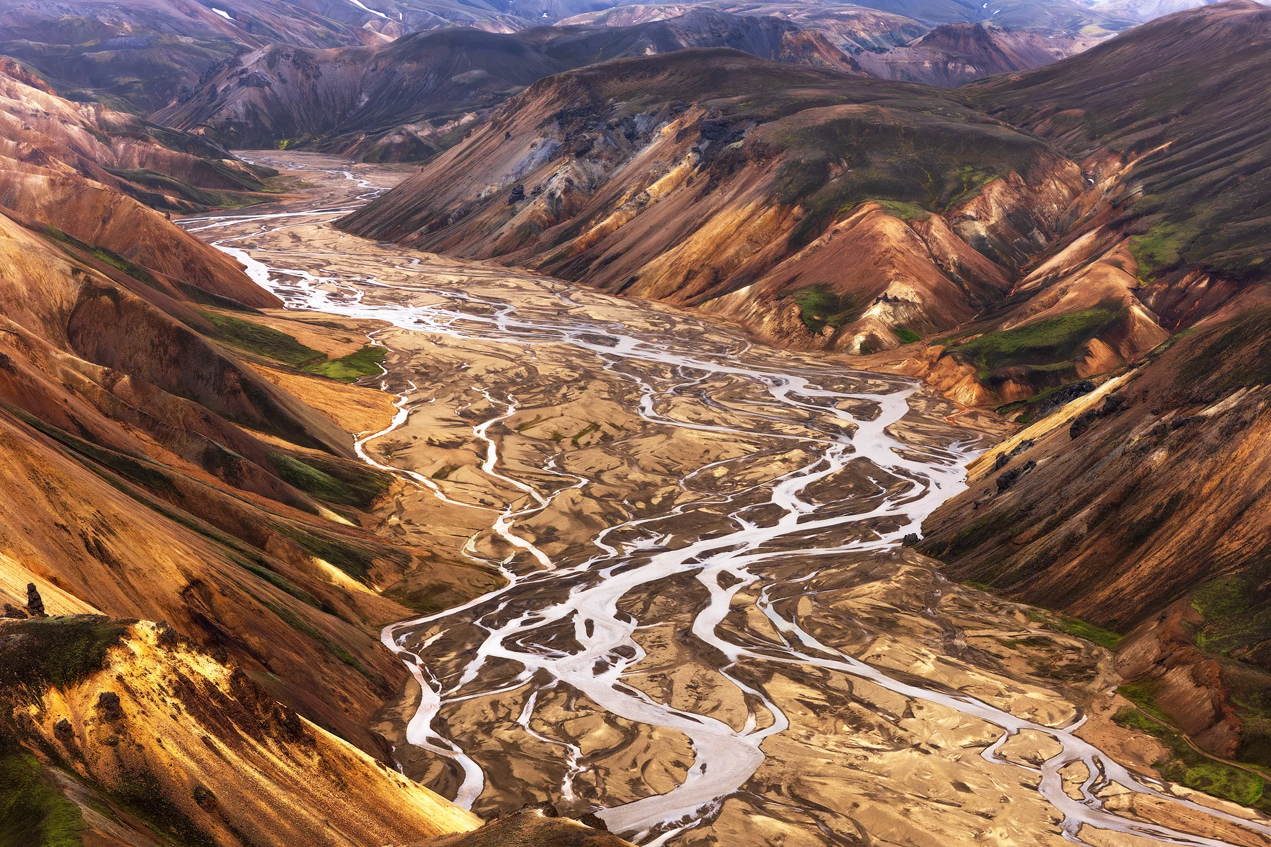 Aerial view of a multicolored mountain valley with winding rivers.
