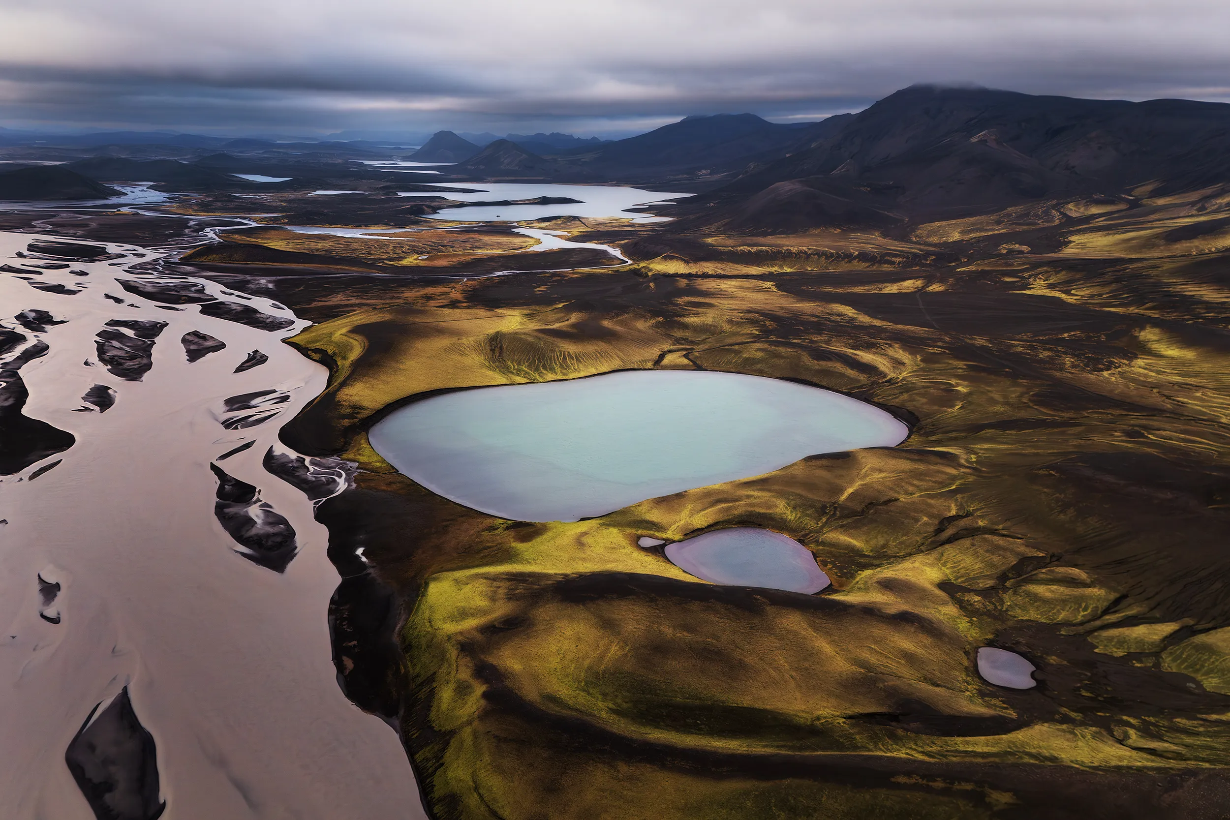 Aerial view of crater lakes, black sand and moss-covered terrain in Iceland.